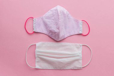 Coronavirüs salgını sırasında sıfır atık. Yeniden kullanılabilir tekstil maskesini seçin. Pembe arka planda tek kullanımlık maske ve yeniden kullanılabilir yüz maskesi. Tek kullanımlık ve el yapımı tekstil maskesi