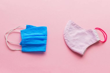 Tek kullanımlık maske ve pembe arka planda yeniden kullanılabilir yüz maskesi. Coronavirüs salgını sırasında sıfır atık. Yeniden kullanılabilir tekstil maskesini seçin. Tek kullanımlık ve el yapımı tekstil maskesi