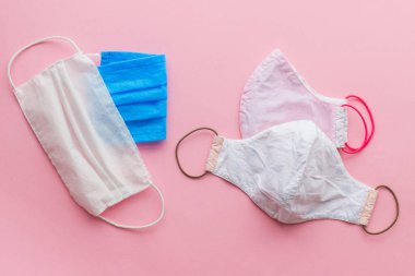 Coronavirüs salgını sırasında sıfır atık. Yeniden kullanılabilir tekstil maskelerini seçin. Pembe arka planda tek kullanımlık maske ve yeniden kullanılabilir yüz maskesi. Tek kullanımlık ve el yapımı tekstil maskesi