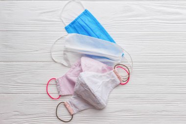 Yeniden kullanılabilir tekstil maskelerini seçin. Beyaz ahşap arka planda tek kullanımlık maske ve yeniden kullanılabilir yüz maskesi. Coronavirüs salgını sırasında sıfır atık. Tek kullanımlık ve el yapımı tekstil maskesi