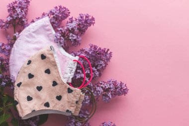 Yeniden kullanılabilir tekstil maskesini seçin. Pembe arka planda leylak çiçekli yeniden kullanılabilir yüz maskesi. El yapımı tekstil maskesi. Coronavirüs salgını sırasında sıfır atık yaşam tarzı