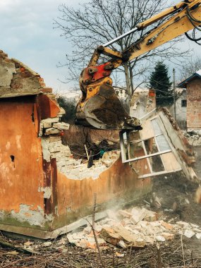 Ev yıkılıyor ve yıkılıyor. Kazıcı kırsaldaki tuğla evi yok ediyor. Buldozer eski tuğlalardan toprak ve çöplerle dolu duvarlardan beton topluyor. Yıkım evi