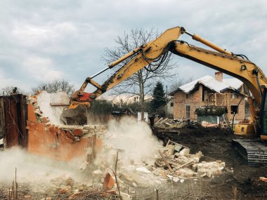 Ev yıkılıyor ve yıkılıyor. Kazıcı kırsaldaki tuğla evi yok ediyor. Buldozer eski tuğlalardan toprak ve çöplerle dolu duvarlardan beton topluyor. Yıkım evi