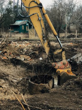 Kazıcı, kırsaldaki ağaçların kökünü kazıyor. Buldozer eski ağaçları, kökleri ve dalları toprak ve çöplerle temizliyor. Kazma makineleri. Bahçe işleri