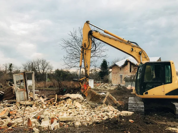 古いレンガや汚れやゴミと壁からコンクリートからブルドーザークリア土地 バックホー機械は家を破壊する 田舎の土地のレンガ造りの家を破壊する掘削機 — ストック写真