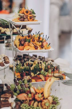 Lokantadaki düğün resepsiyonunda masada taze meyveler var. Lüks yemek servisi. Sağlıklı meyve büfesi. Muz, portakal, üzüm, şeftali ve elma.