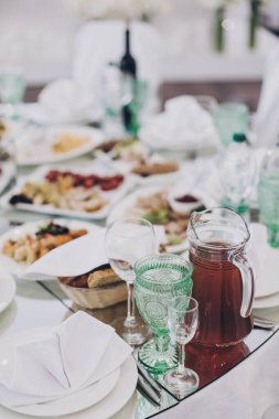 Restorandaki resepsiyonda lüks bir düğün masası. Şarap için şık bardaklar, peçeteli tabaklar, çatal bıçak takımı ve masalarda yemek. Lüks yemek servisi. Noel ziyafeti