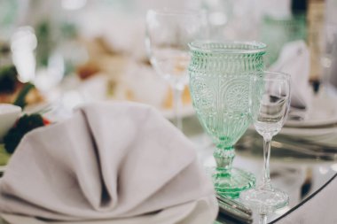 Restorandaki resepsiyonda lüks bir düğün masası. Şarap için şık bardaklar, peçeteli tabaklar, çatal bıçak takımı ve masalarda yemek. Lüks yemek servisi. Noel ziyafeti