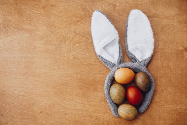 Şık paskalya yumurtaları kırsal masada, tavşan kulaklı, yazı için yer var. Ahşap arka planda doğal boyanmış paskalya yumurtaları. Tatil kartı