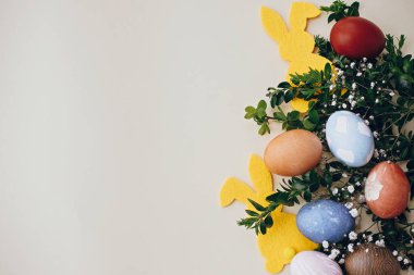 Mutlu Paskalyalar. Şık paskalya yumurtaları, sarı tavşancık, sarı kağıtta bahar çiçekleri, yazı için yer. Doğal boyanmış paskalya yumurtaları ve tavşan süslemesi..