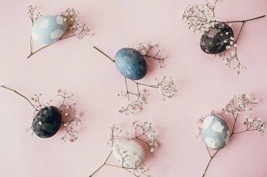 Paskalya yumurtaları ve bahar çiçekleri pembe kağıt üzerinde düz konum, yazı için alan. Modern doğal boyanmış mavi ve mermer paskalya yumurtaları. Mutlu Paskalyalar. Tebrik kartı şablonu