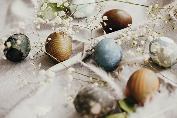 在乡村餐桌上放上美味的复活节彩蛋 天然色彩艳丽的彩蛋 春白色的花朵和羽毛在农村纺织品背景上 案文的篇幅 — 图库照片
