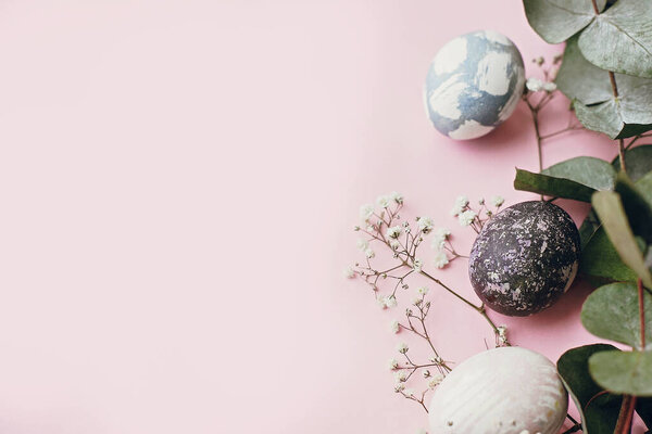 Стильные пасхальные яйца, весенние цветы, веточка эвкалипта на розовой бумаге, место для текста. Современные натуральные окрашенные голубые и мраморные пасхальные яйца. Счастливой Пасхи. Шаблон поздравительной открытки
