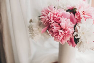 Kırsal ahşap pencere pervazında güneşli bir ışıkta hoş bir şakayık buketi. Ahşap arka planda vazoda pembe ve beyaz şakayıklar. Merhaba bahar. Anneler Günün kutlu olsun.