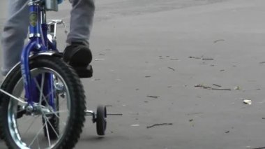 Çocuk bisikleti süren bir çocuğun ayaklarına asfalt pedin üstünde yakın plan.