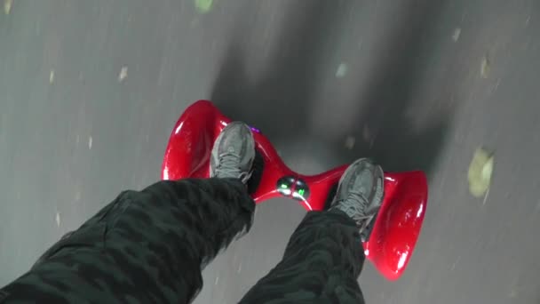 紅葉に覆われたアスファルトの道路に赤いホバークラフトに乗る男の足 — ストック動画