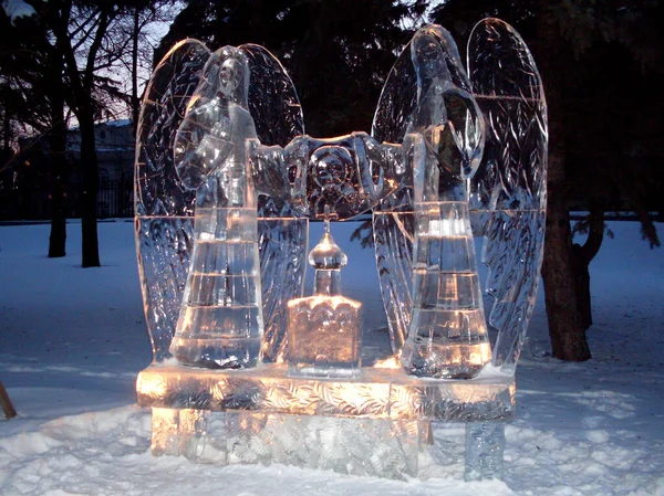 Ледяная Скульптура Освещенная Светодиодами Виде Двух Ангелов Наклонившихся Над Миниатюрным — стоковое фото