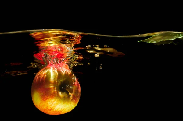 Äpfel in Wasser mit Spiegelung und Spritzer Stockfoto