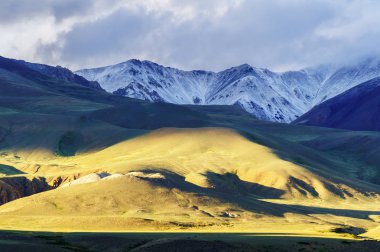 Düşük güneş ışık desen tepe ve kar kaplı dağ zinciri