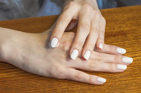 Φροντίδα του γυναικείου χέρια με ένα λευκό μανικιούρ. Εφαρμογή της κρέμας — Φωτογραφία Αρχείου