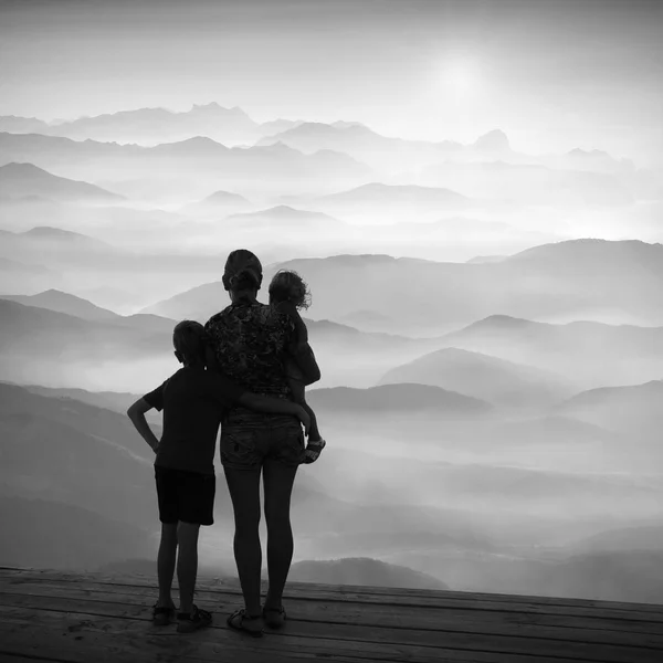 Family watching sunrise above the mountain valley. Black and whi — Stock Photo, Image