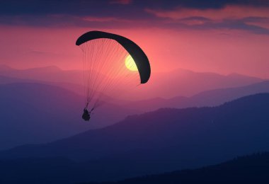 Uçan paraglide bir ışık gündoğumu silüeti