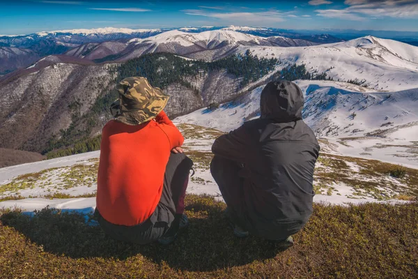 Туристы сидят на холме и наслаждаются горами — стоковое фото
