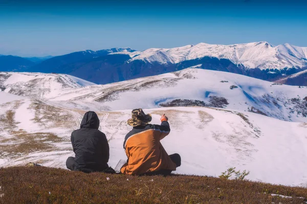 Двое туристов сидят на холме и наслаждаются горным валом. — стоковое фото