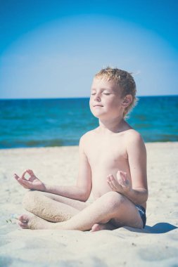 Çocuk denize sıfır bir plaj üzerinde meditasyon. Instagram biçimleşmeden