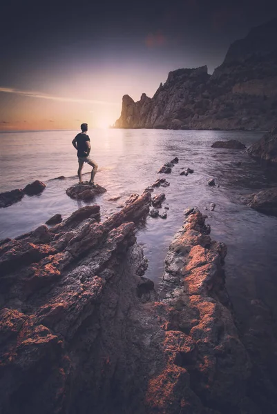 Mann steht auf einem Stein in einer Meeresbucht. Instagram-Stilisierung — Stockfoto