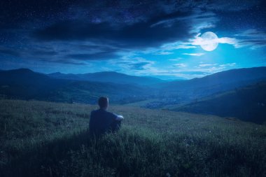 İnsan bir tepe üzerinde oturan ve aya düşüyor keyfini çıkarın