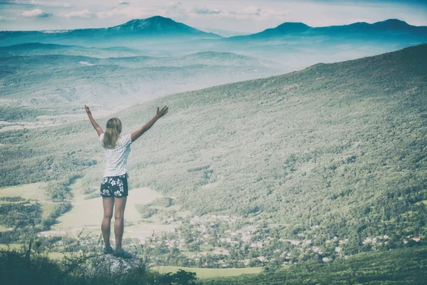 En glad kvinde, der står på en klippekant. Instagram stilisering - Stock-foto