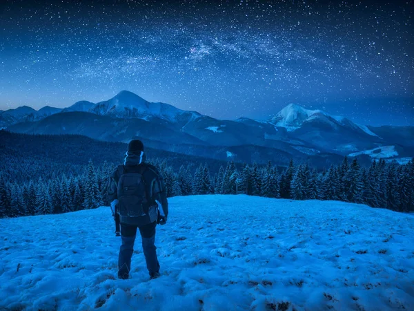 Caminante con mochila de pie en una colina cubierta de nieve —  Fotos de Stock