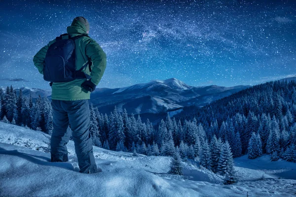 Альпинист, стоящий ночью на снежном склоне — стоковое фото