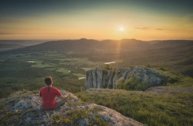 Kayalık bir tepe üzerinde oturan turist