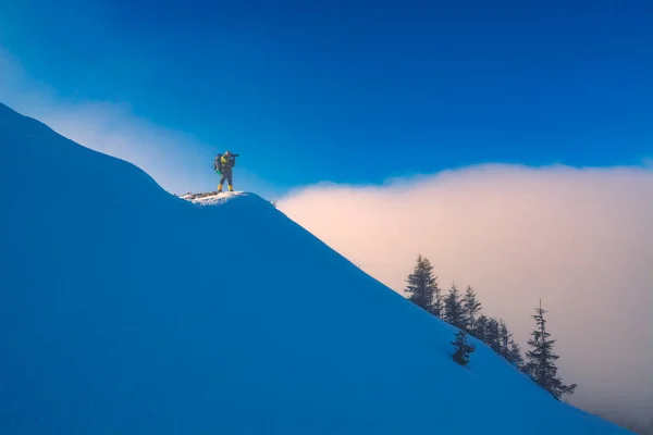 Фотограф, стоящий на снежном холме — стоковое фото