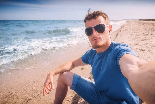 Homme en lunettes de soleil prenant selfie sur une plage de la mer — Photo