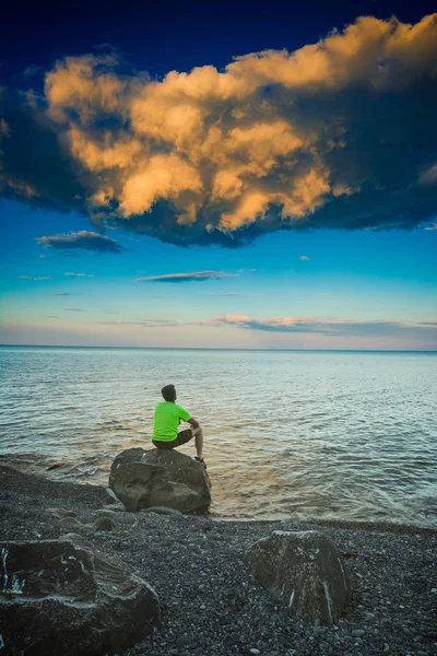 남자는 바다에서 돌에 앉아 — 스톡 사진