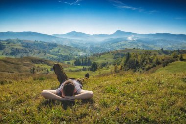 Man lies on a hill in a grass and enjoy the valley