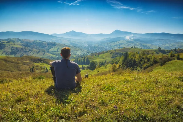 Un homme assis sur une colline dans une herbe — Photo