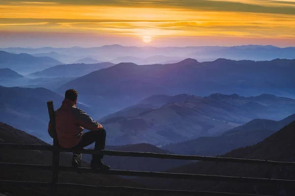 Ember természetjáró ül a kerítésen, és élvezi a napfelkeltét — Stock Fotó
