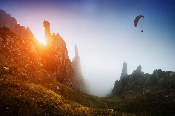 Silhueta de parapente sobre o vale nebuloso da montanha — Fotografia de Stock