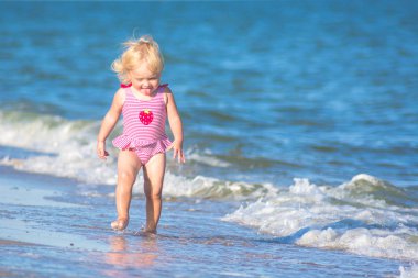Küçük komik kız denize sıfır plaj tarafından yürüyüş