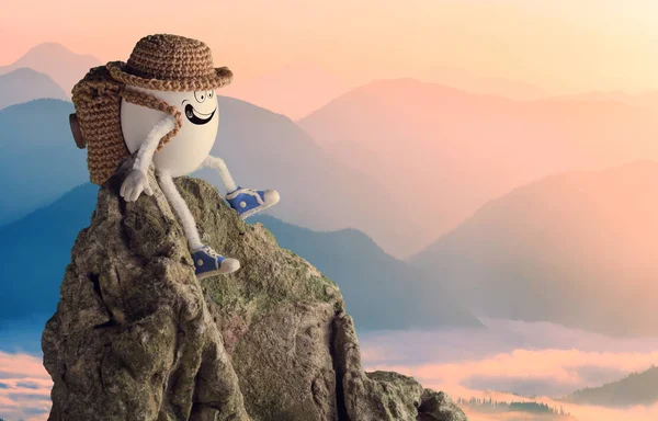 Caminante feliz huevo en un sombrero divertido sentado en un acantilado — Foto de Stock