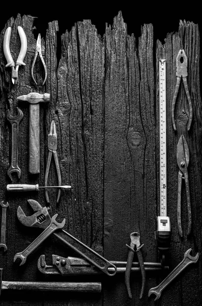 Много различных инструментов на старом деревянном фоне. Черный и белый — стоковое фото