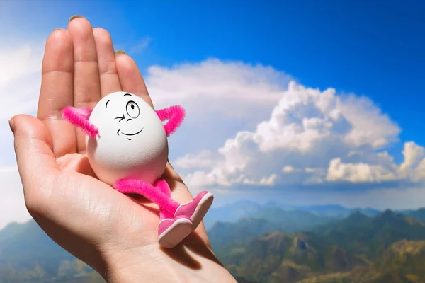 Egg girl sitting on a woman hand against the mountains — Stock Photo, Image