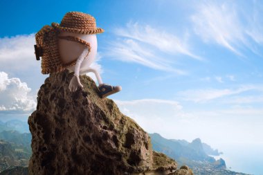 Komik şapkalı bir uçurumun üzerinde oturan bir Paskalya yumurtası uzun yürüyüşe çıkan kimse