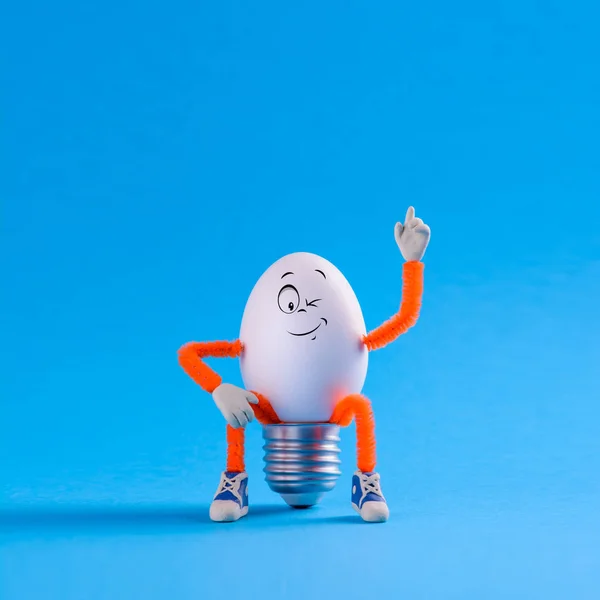 Winking Easter egg toy in the shape of a light bulb on a blu — Stock Photo, Image