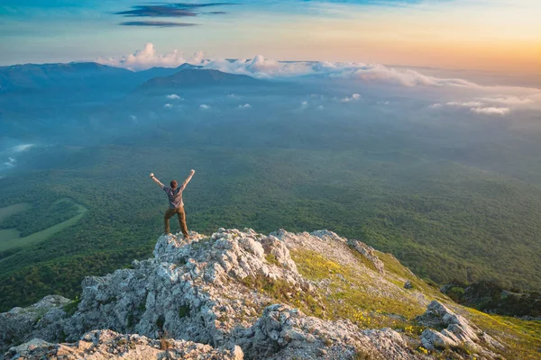Mladý šťastný muž, stojící na vrcholu skalnaté hory — Stock fotografie