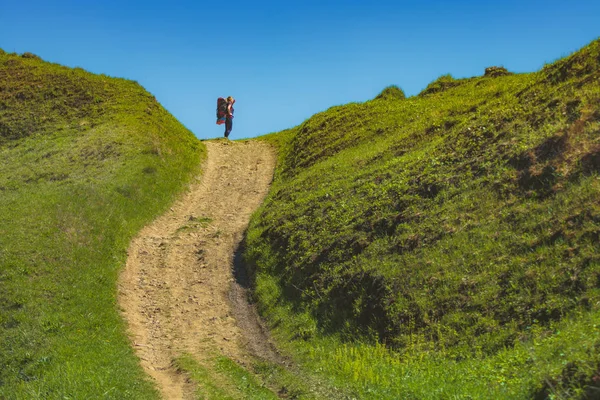 Flicka hiker med ryggsäck mot blå himmel — Stockfoto